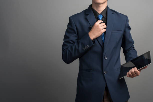 fermez-vous vers le haut de l’homme d’affaires dans le procès bleu utilisant une cravate sur le fond gris - suit necktie close up gray photos et images de collection