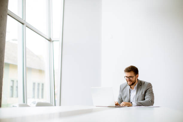istock Young man working on laptop in bright office 1293871355