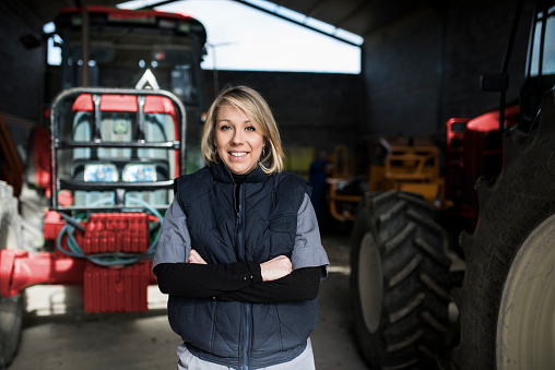 Woman posing in rural tractors warehouse. Smiling looking at camera