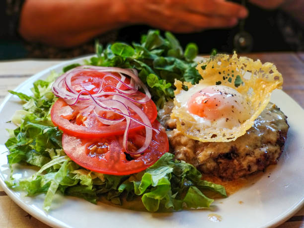 Delicious hamburger steak with cheese, fried egg and salad