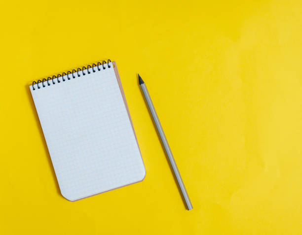 istock Blank notepad on yellow background with yellow pen. 1293878973