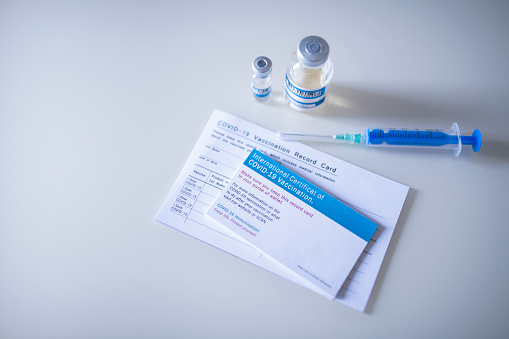 Certificate of vaccination, vaccination record card and COVID-19 vaccines on clear background.