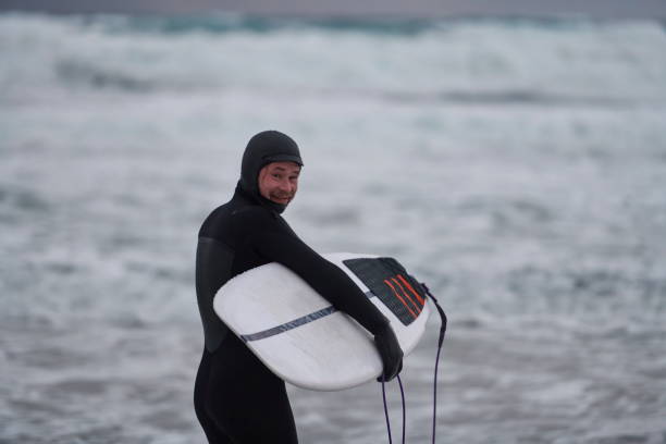 istock Arctic surfer going by beach after surfing 1293880437