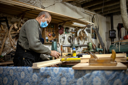 Senior carpenter sanding and preparing timbers for further crafting in the workshop