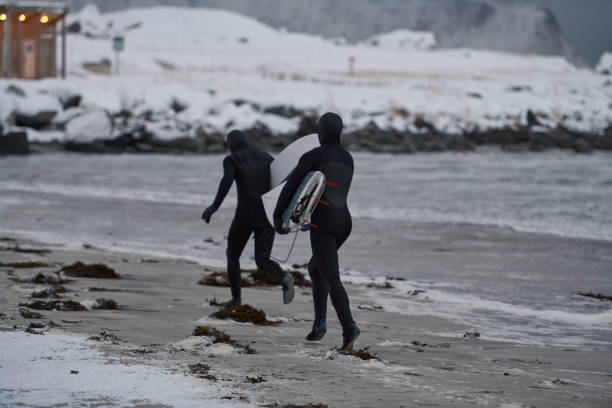 istock Arctic surfers running on beach after surfing 1293881466