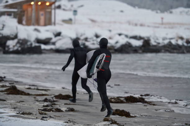 istock Arctic surfers running on beach after surfing 1293882334