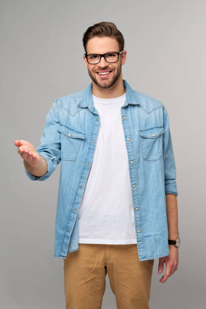 istock Happy Young Man Presenting standing grey White Background 1293887260