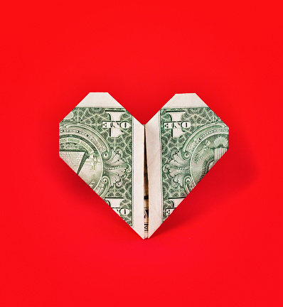 US $1 banknote folded into a heart shape, on a bright red background.