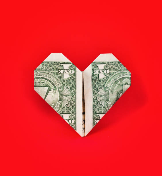 The love of money: US dollar bill folded origami-style into the shape of a heart US $1 banknote folded into a heart shape, on a bright red background. making money origami stock pictures, royalty-free photos & images