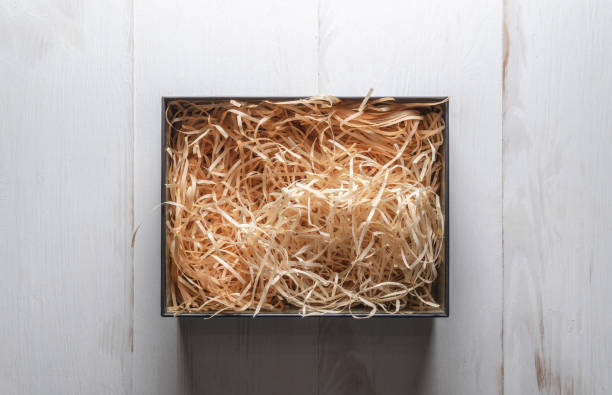 istock Top view of an open box with packing sawdust. Gift wrapping on a light table. 1293891403