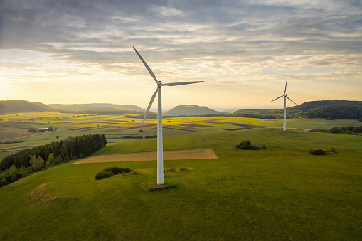 Turbina eólica de energía alternativa en el paisaje verde del verano al atardecer photo