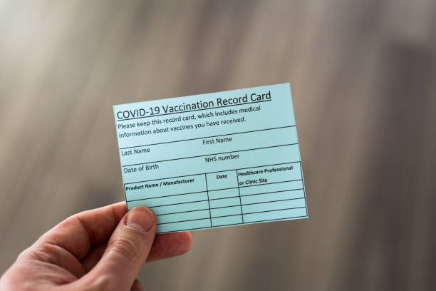 istock Hand holding covid-19 vaccination record card 1293894029