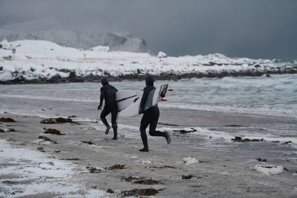 istock Arctic surfers running on beach after surfing 1293894091