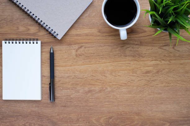 istock Top view from above of Blank open notebook, pen and coffee on wood table background. Workplace for creative work of designer at home. Flat lay, Business-finance or education concept with copy space. 1293894112