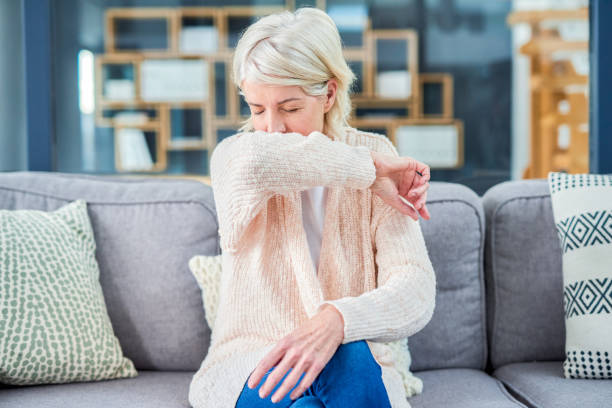 Could it be more than a cough? Shot of a senior woman feeling ill on the sofa at home bronchitis stock pictures, royalty-free photos & images