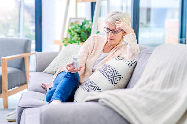 Educate before you medicate Shot of a senior woman reading the label on a medicine container at home medicate stock pictures, royalty-free photos & images