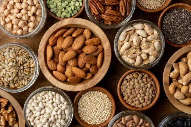 Healthy nuts, seeds and legumes (beans) on a wood background. Vegan proteins. Bulk foods.