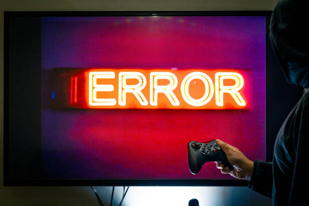 istock Man holding a controller in front of a screen showing an error message as a game crashes due to bugs in unfinished software 1293898583