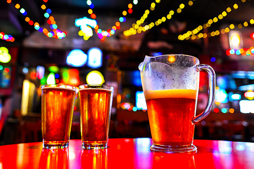 Pitcher of Beer and Full Pint Glasses - Bokeh Light Background