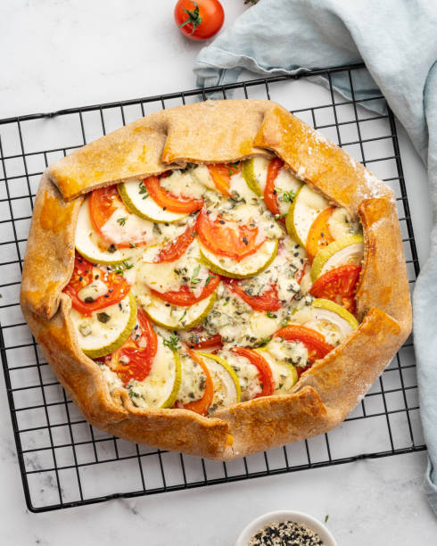 Homemade savory galette with vegetables, wholegrain pie with tomatoes, zucchini, blue cheese Homemade savory galette with vegetables, wholegrain pie with tomatoes, zucchini, blue cheese Gorgonzola. Rustic crust crostata on dark linen textile tablecloth. Top view, vertical crostata photos stock pictures, royalty-free photos & images