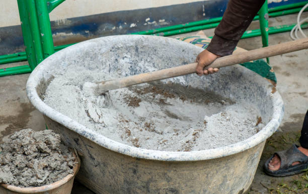istock Asian man hands working and holding hoe mix cement and sand in a gray plastic bowl 1293899621