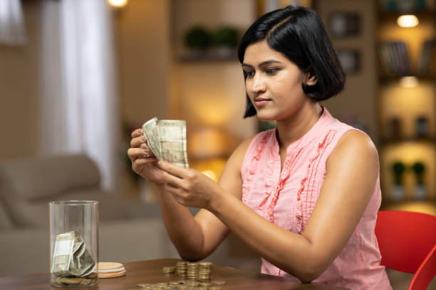 Young woman - stock photo Indian, Indian Ethnicity, lifestyle, domestic life, counting coins stock pictures, royalty-free photos & images