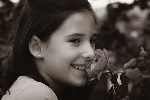 Sweet child posing near flower. Innocence, taking care of nature concepts, black and white photography