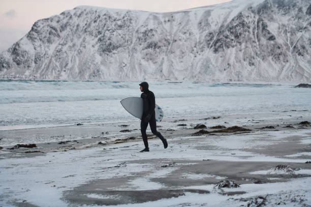 istock Arctic surfer going by beach after surfing 1293912513