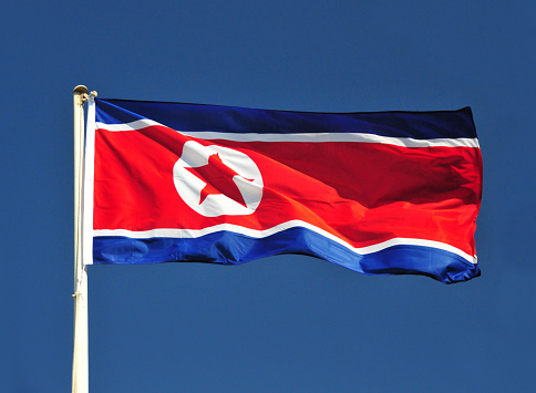 Pyongyang, North Korea / DPRK: the flag of the Democratic People's Republic of Korea flutters in the wind against blue sky, also known as the Ramhongsaek Konghwagukgi - North Korean Flag design: the blue stripes stand for the people's desire for peace, the red one symbolizes the revolutionary spirit of the struggle for socialism, and white - a traditional Korean color - represents the purity of the ideals of (North) Korea and national sovereignty. The five-pointed star signifies the happy prospects of the people building socialism under the leadership of the Korean Worker's Party. The white disc suggests the yin and yang symbol (\