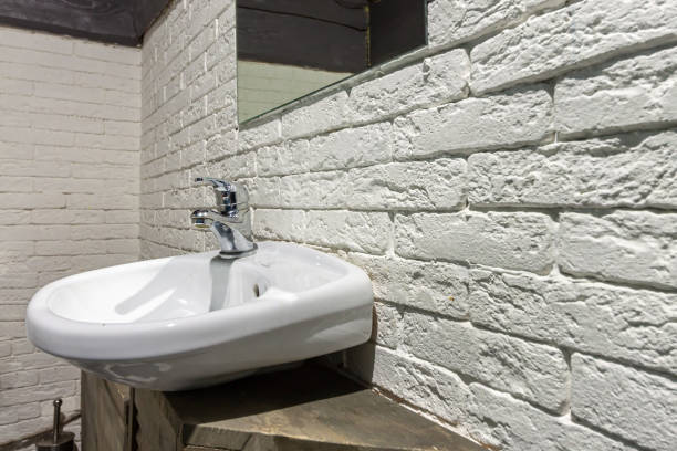 White ceramic bathroom sink with mirror on loft brick wall background stock photo