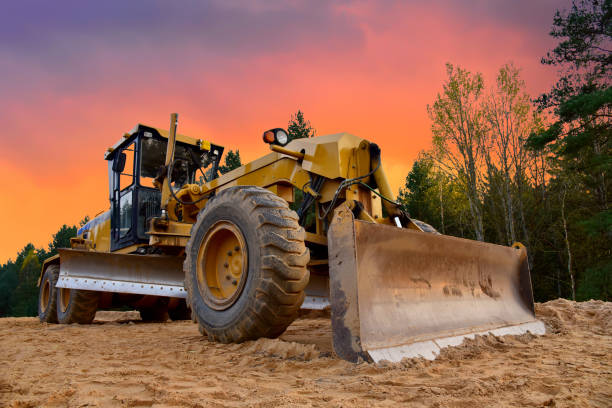 Motor Grader on road construction in forest area. Greyder leveling the sand, ground and gravel during road work Motor Grader on road construction in forest area. Greyder leveling the sand, ground and gravel during road work. Heavy machinery and construction equipment for grading. Earthworks grader machine road scraper stock pictures, royalty-free photos & images