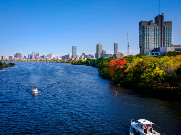 paysage urbain de boston avec le feuillage d’automne et les bateaux de course dans la rivière charles - boston skyline charles river blue photos et images de collection