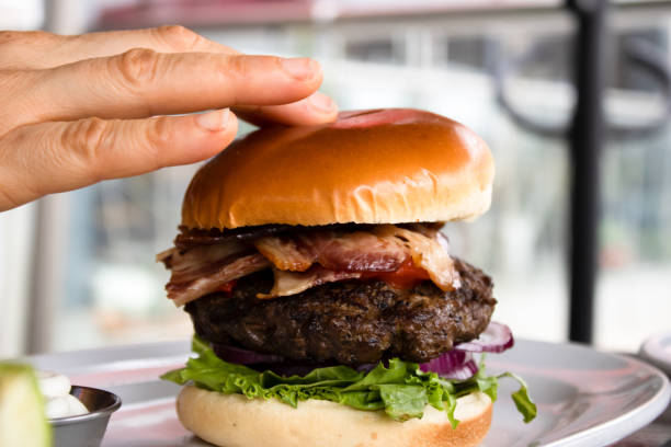 istock Hand on the bun of a bacon burger 1293923857