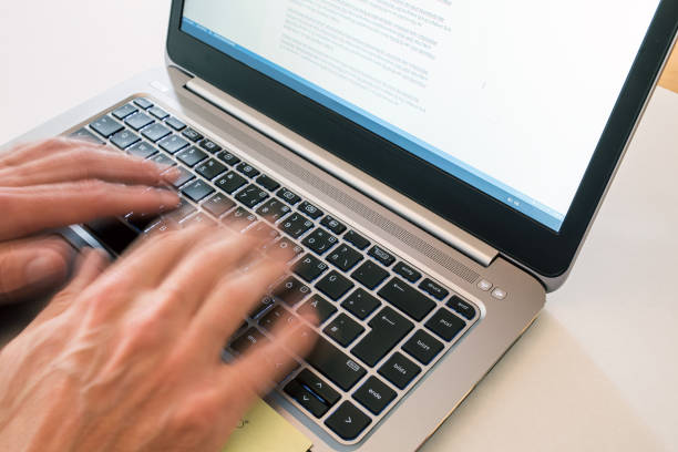 Close-up of fingers in motion typing on the keyboard of a laptop computer.