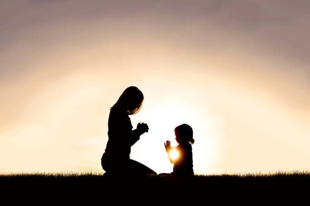 istock Mother Praying with her Young Child Outside at Sunset. 1293930819