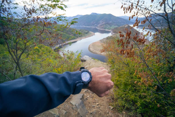 Tourist relaxing in the Nature, hiking in the highlands. Looking at a beautiful mountain view of a mountain river. Checking what the time is. punto de vista. perspectiva personal de un hombre mirando su reloj. hermosa vista del paisaje en el fondo en frente de él. de vuelta a la naturaleza. turista de senderismo en las montañas mirando a una hermosa vista. disfrute al aire libre en un día de