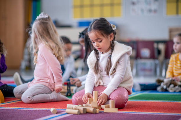 istock Young Caucasian girl playing with blocks in classroom 1293937567