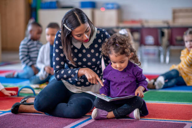 istock Preschool teacher helping student read 1293937574