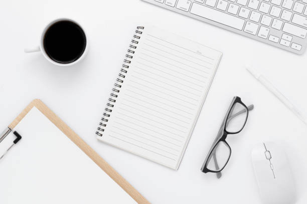istock Minimal Office desk table top view with office supply and coffee cup on a white table with copy space, White color workplace composition, flat lay 1293947512