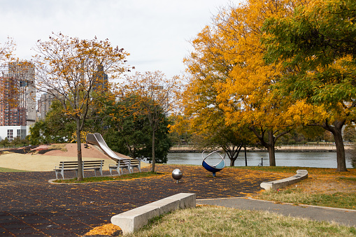 An empty playground with colorful trees during autumn along the East River at Rainey Park in Astoria Queens New York