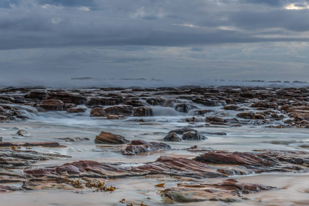 istock Rock platform, cascades and splashes with rain clouds by the seaside 1293977377