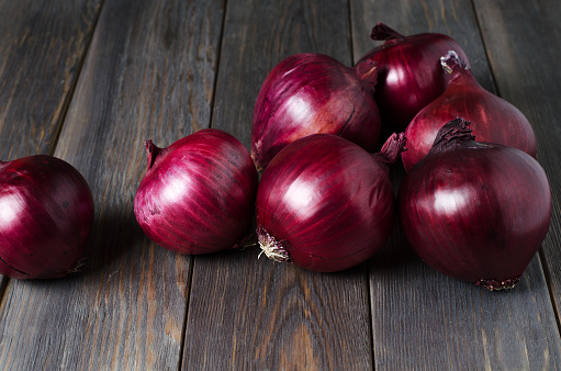 Lots of red onions on a brown wooden background. Flat top view