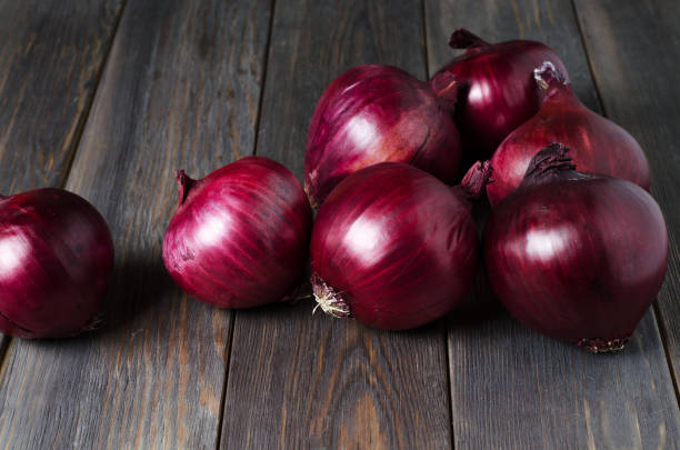 Lots of red onions on a brown wooden background. Lots of red onions on a brown wooden background. Flat top view spanish onion stock pictures, royalty-free photos & images