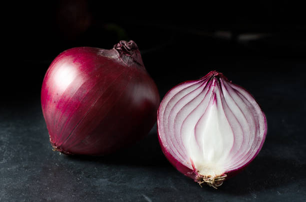 istock Red onion. Large onion and sliced. Black background. Side view. 1293982592