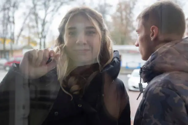 A young girl knocks her fist on the glass door.