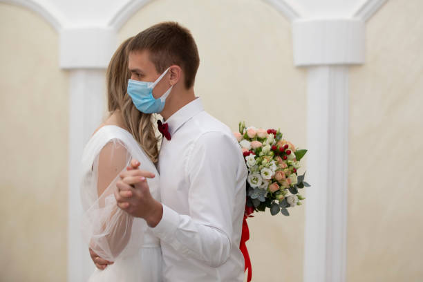 istock Bride and groom wearing medical masks. 1293986148