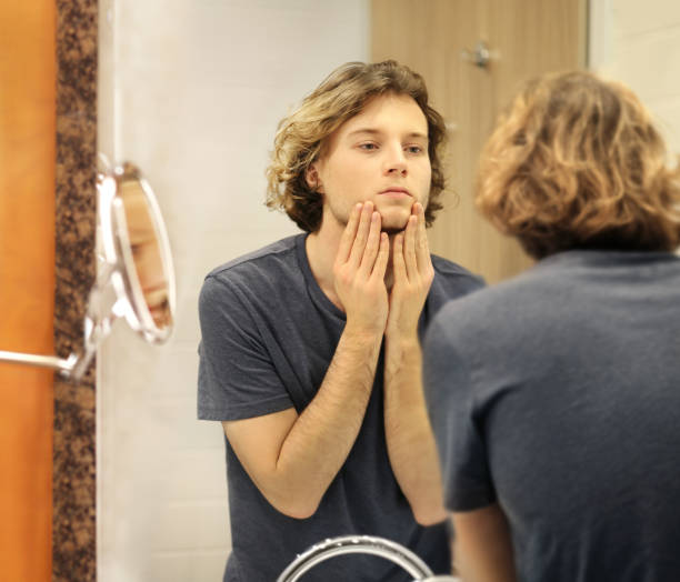 istock Applying the cream.young man looking in the mirror 1293991278