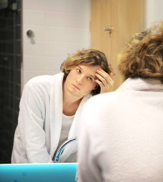 istock Applying the cream.young man looking in the mirror 1293991286