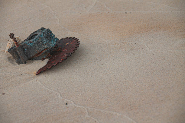 Scrap metal garbage half buried in the sandy beach, shows environmental damage and pollution