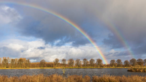 rainbow over a lake in the broekpolder, vlaardingen, the netherlands - end of the rainbow imagens e fotografias de stock
